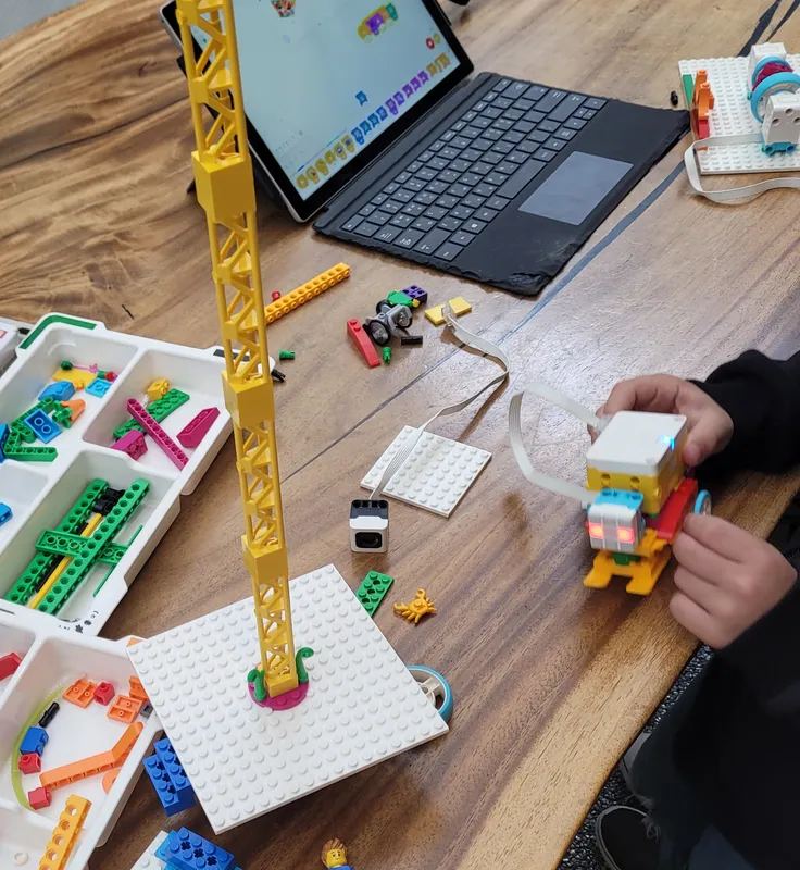 Young children building with LEGO and exploring on a laptop at C.Lab Academy